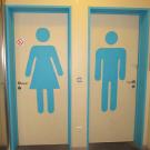Voor de aanduiding van de toiletten wordt er gewerkt met de herkenbare pictogrammen voor mannen en vrouwen. De pictogrammen hebben een contrasterende kleur ten opzichte van de kleur van het deurblad. (Jeugdcentrum Ahoy, Wijnegem)