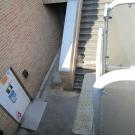 De toegang tot het jeugdhuis is gelegen op een kelderverdieping. Er is een combinatie van een trap en een lift om deze toegang voor iedereen toegankelijk te maken. (Jeugdhuis Bascule, Eversel)