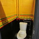 Bij dit gewone toilet werd de achterwand goed contrasterend uitgevoerd ten opzichte van de witte toiletpot. (Jeugdhuis Club 9, Koersel)